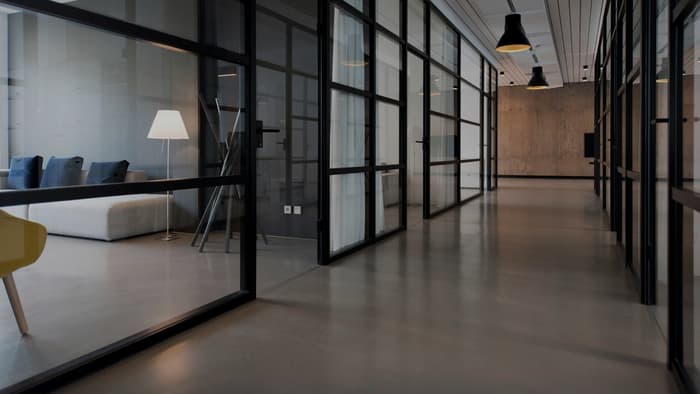 A quiet office corridor lined with glass partitions